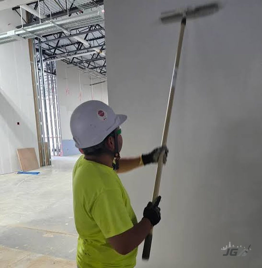Painter rolling wall in an open commercial office space under construction