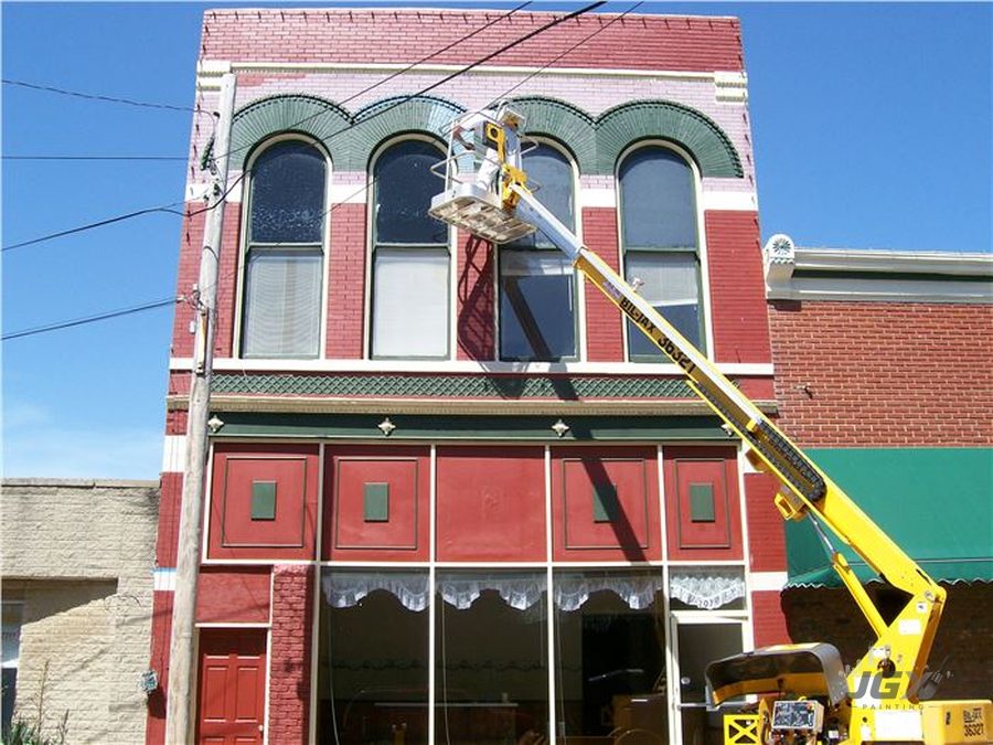 Boom lift used to paint upper windows of a historic brick storefront building