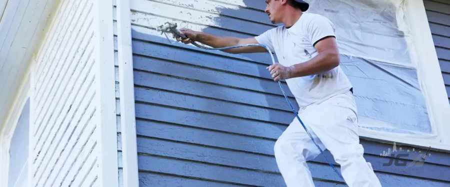 Painter using an airless sprayer to repaint horizontal siding
