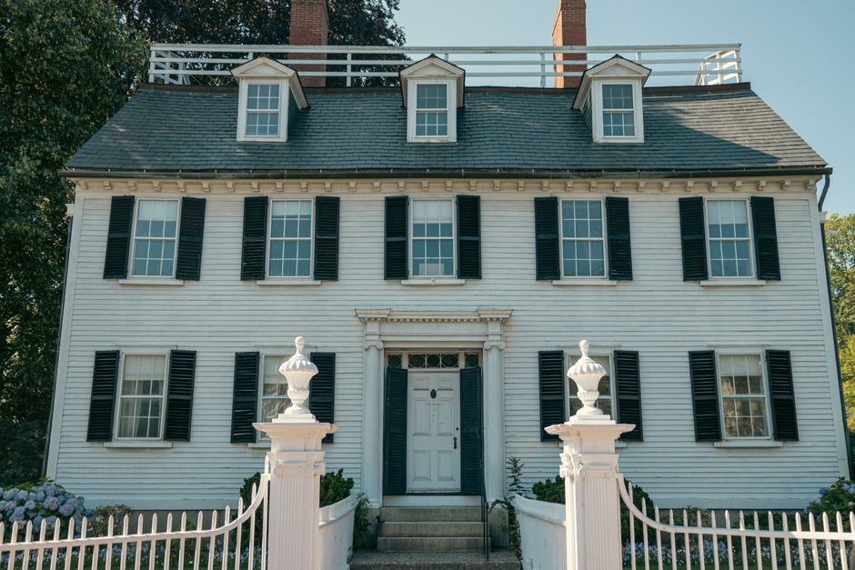 Elegant Colonial-style house with black shutters and white picket fence.